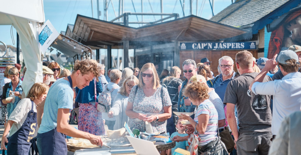 Crowds of people watching a chef cook fish 